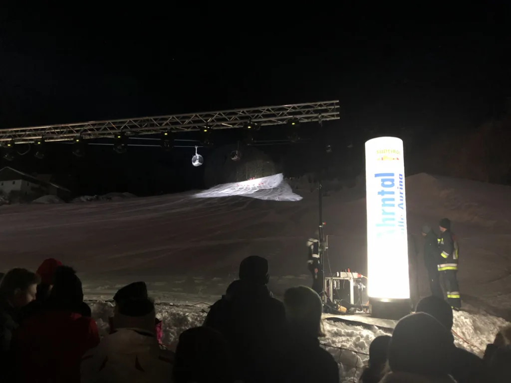 Zuschauer vor der beleuchteten Bühne bei Nacht.